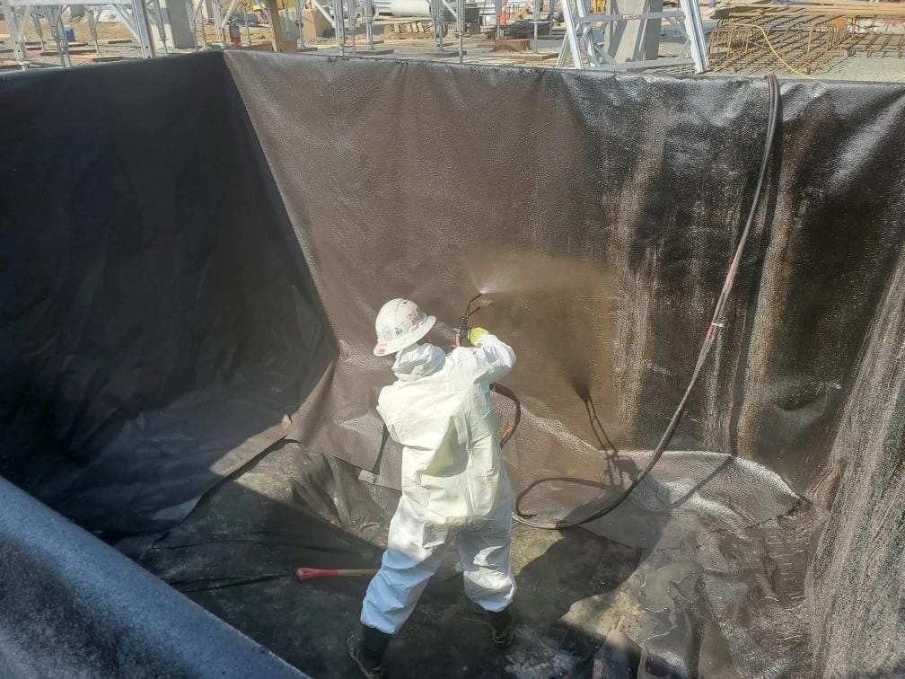 Worker Installing Radon Mitigation System Liner in Basement
